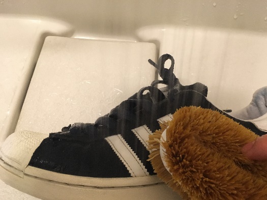 黒い靴をたわしで洗っている写真